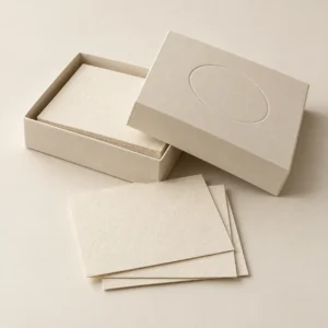 AI concept: an ivory box lid and paper samples with an unprinted recessed oval impression.