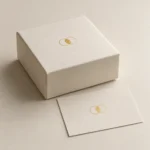 AI concept: an ivory box and paper sample with a small gold-coloured reflective foil motif.
