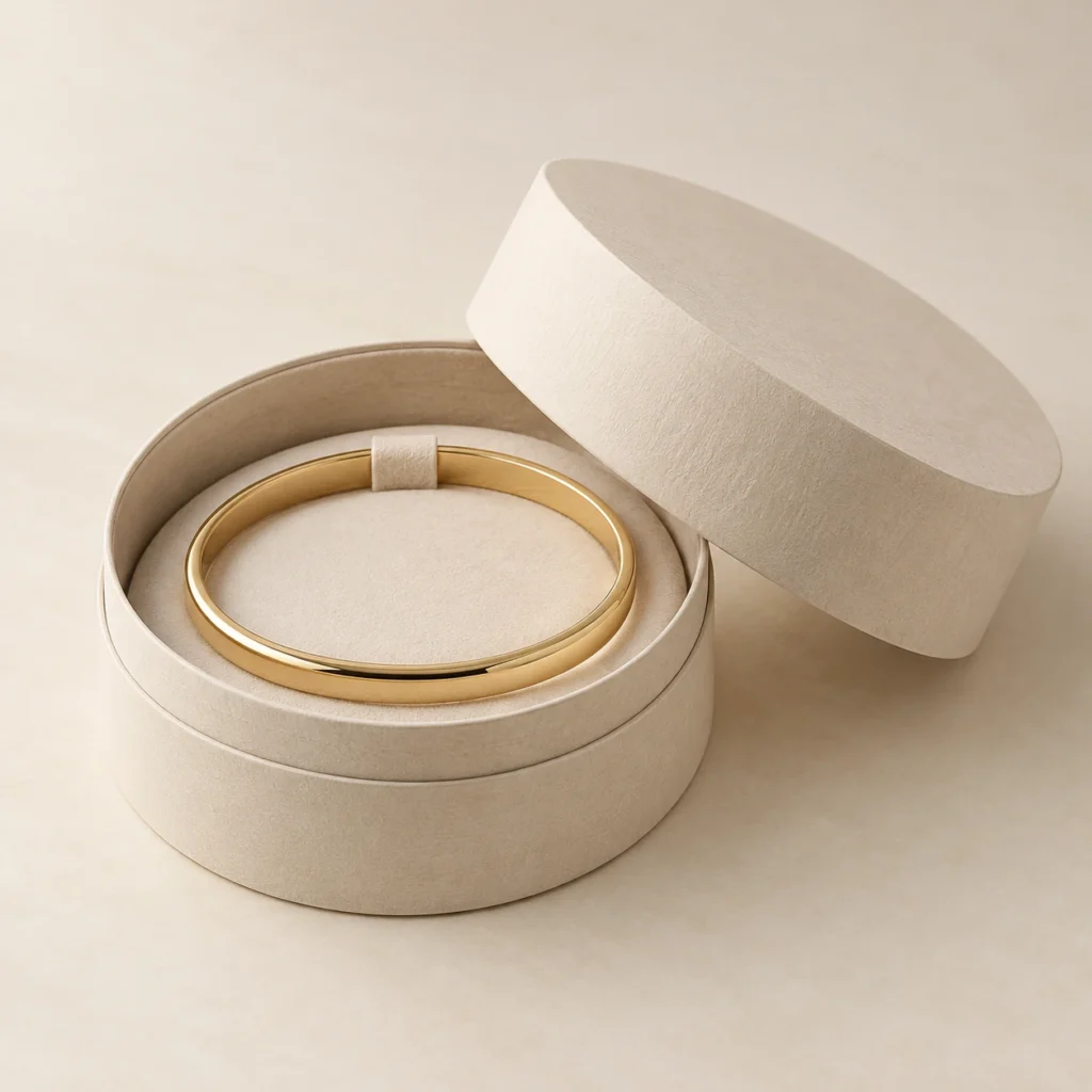 AI concept: round ivory bracelet box with a gold-coloured bangle, catalog view.