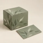 AI concept: a muted sage carton and paper sample with a botanical pattern and a matte finish.