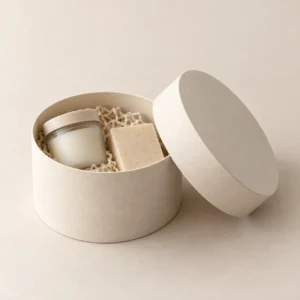 AI concept: round ivory gift box containing a jar, a small box and loose filler, catalog view.